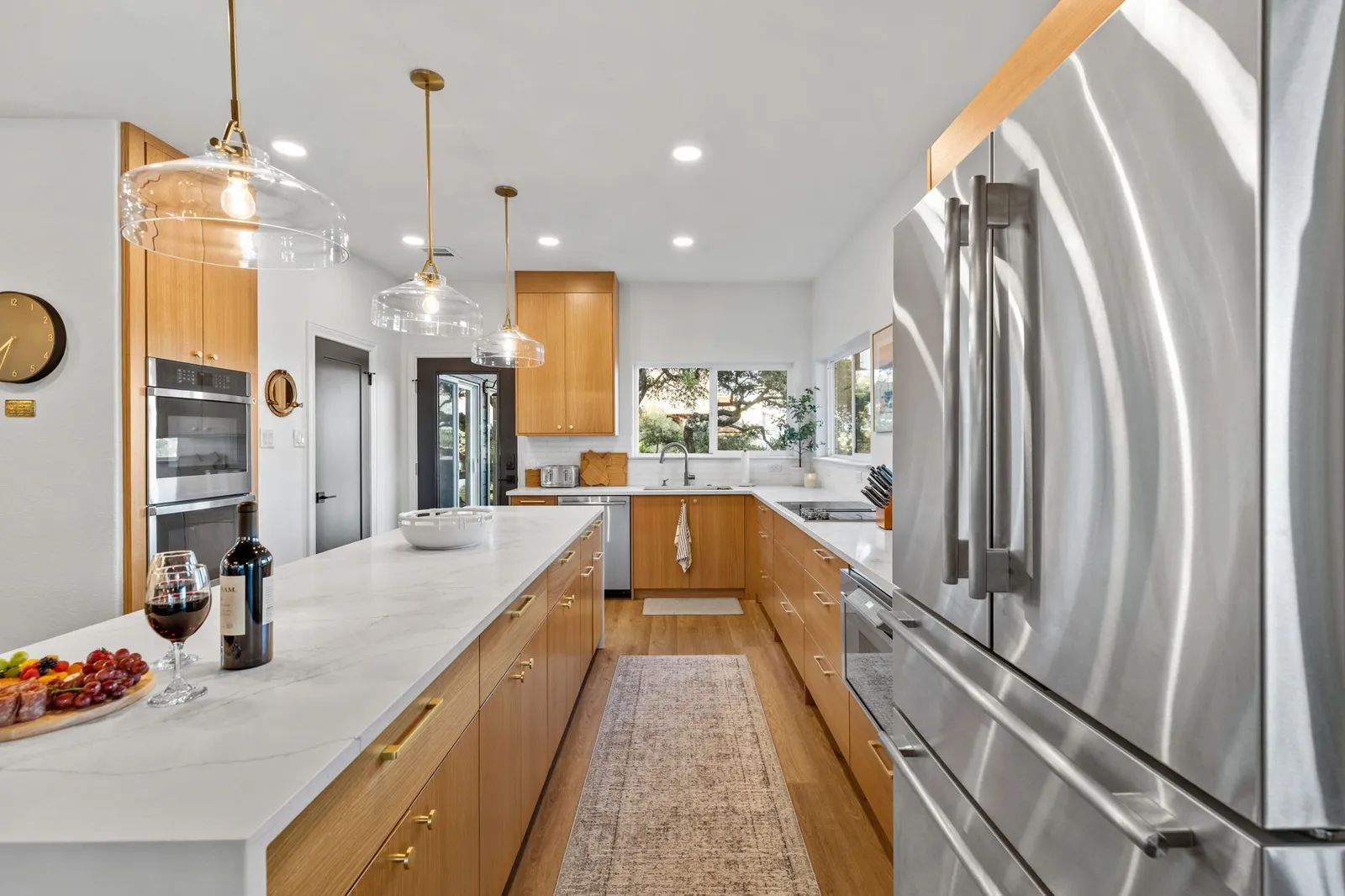 Bright kitchen with white-oak cabinets and a marble island finished by Ranger Painting in west Austin