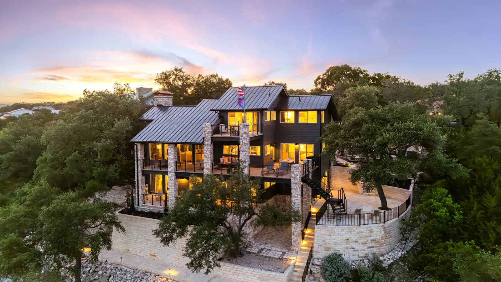 Large Hill Country home with stone columns and dark siding painted by Ranger Painting in west Austin