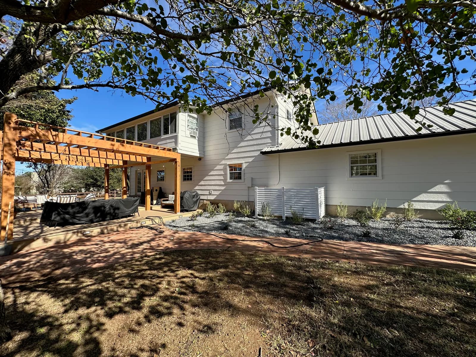 White lap-siding rear elevation with a cedar pergola, repainted by Ranger Painting in Austin