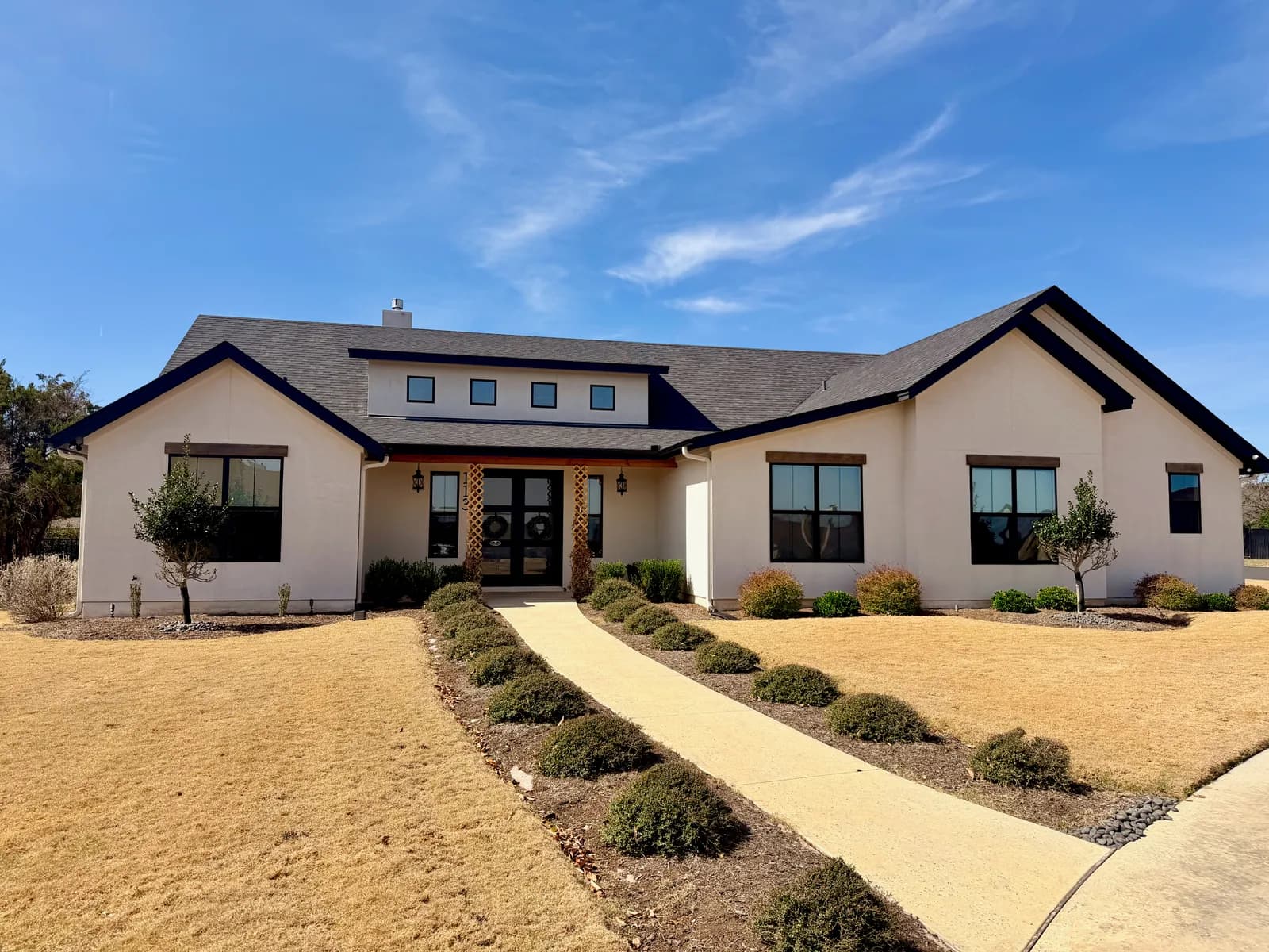 Single-story white stucco modern-farmhouse home with black-framed windows painted by Ranger Painting in Austin