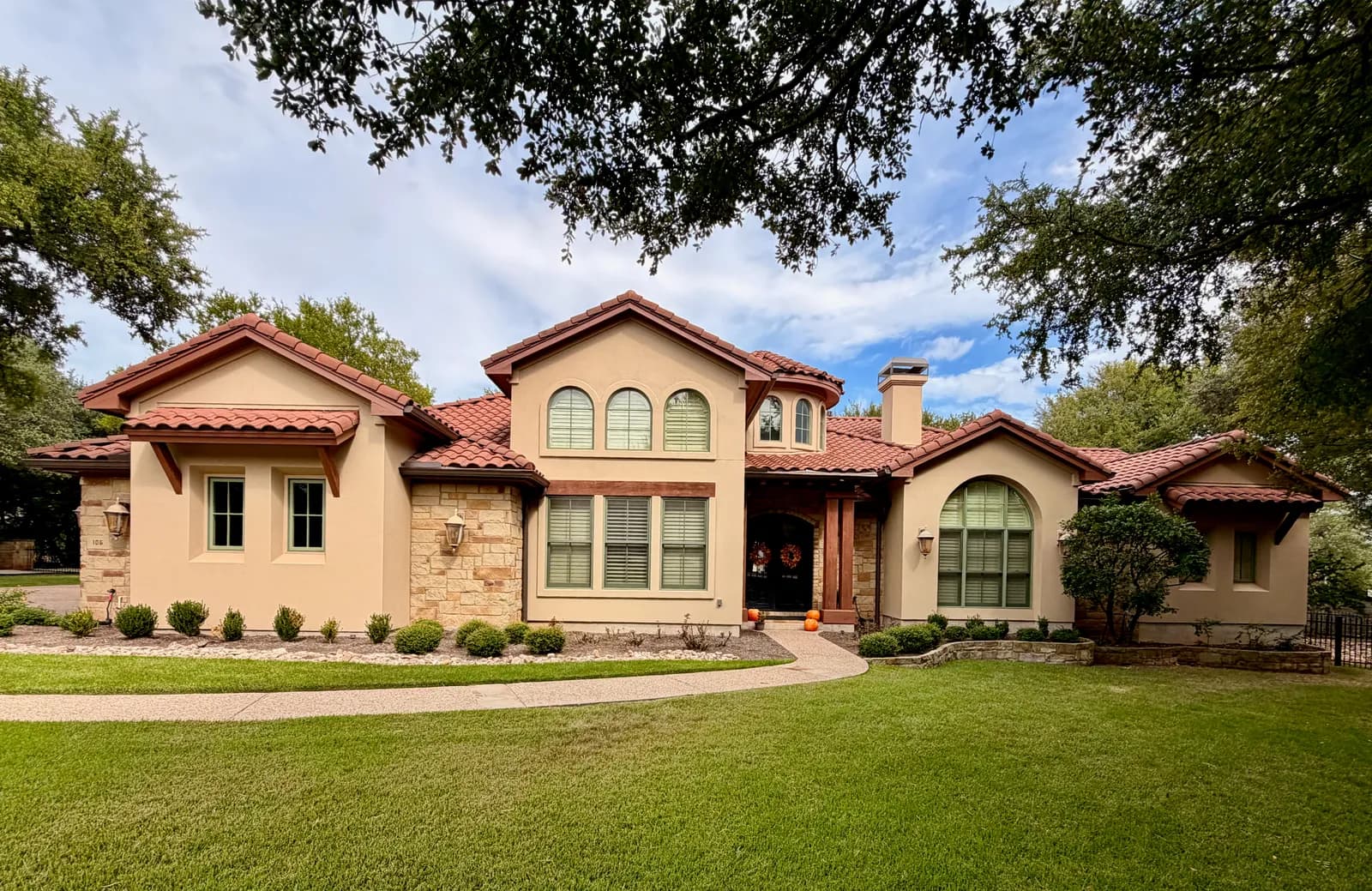 Tan stucco Mediterranean-style home with a clay tile roof painted by Ranger Painting near Lakeway
